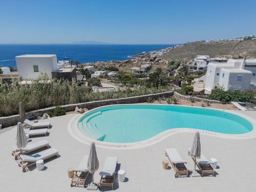 a swimming pool with chaise lounges and chairs at The Mykonian Escape in Mikonos