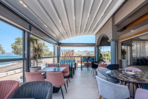 a restaurant with tables and chairs and large windows at Christina Beach Hotel in Kissamos