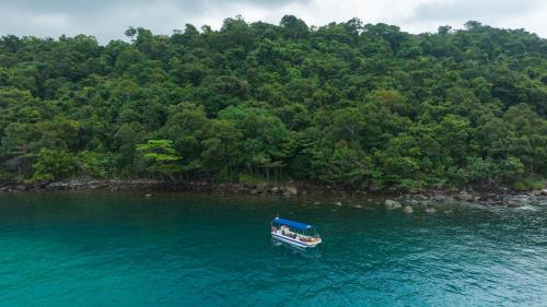 a boat in the water next to a forest at Mafiya Resort in Koh Rong Island