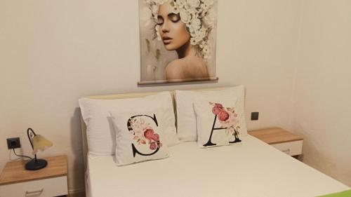 ein Schlafzimmer mit einem Bett mit zwei Kissen und einem Gemälde in der Unterkunft Anastelia Apartments - 2 in Olympiada