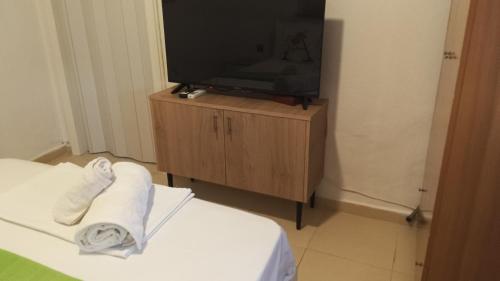 ein Hotelzimmer mit einem TV und Handtüchern auf dem Bett in der Unterkunft Anastelia Apartments - 2 in Olympiada