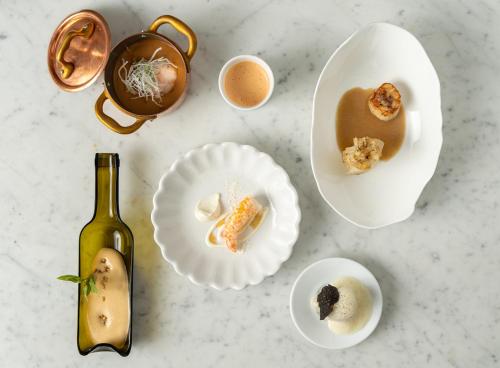 a table with plates of food and a bottle of wine at Le Domaine Du Colombier in Malataverne