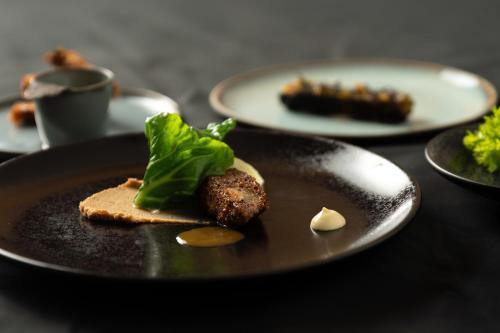 a black plate with food on a table at Le Domaine Du Colombier in Malataverne