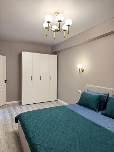 una camera con letto verde e lampadario a braccio di Трехкомнатная квартира с хорошим ремонтом a Almaty