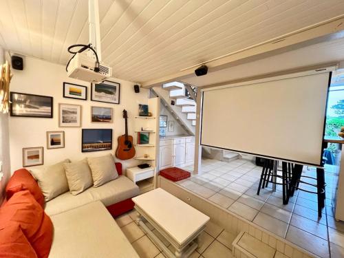 a living room with a white couch and a screen at Le 140, Surf et Confort in Seignosse