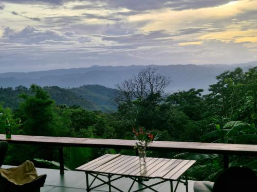 a table on a balcony with a view of the mountains at Doichang Riverhouse in Ban Huai Khai