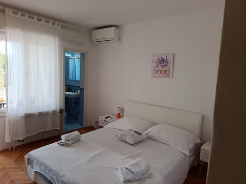a bedroom with a white bed with two towels on it at APARTMAN I SOBE MARIJANA in Rab