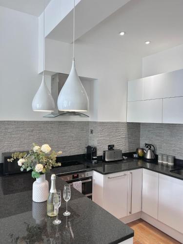 a kitchen with white cabinets and a black counter top at Brighton Rock Retreat in Brighton & Hove