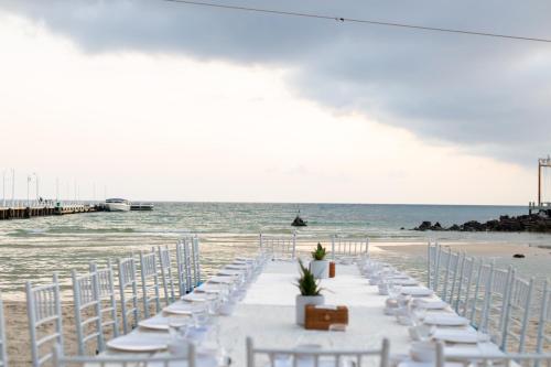 a long table with white chairs on the beach at Mafiya Resort in Koh Rong Island