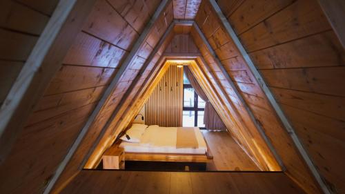 a bed in a wooden room with a window at Vălari Frame in Păltiniş