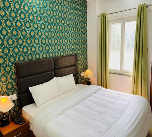 a bedroom with a bed and a green wall at Hotel Namo Gange in Rishīkesh