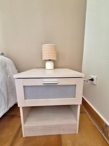 a white bedside table with a lamp on it at Mon Eden in Meynes