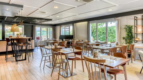 a restaurant with tables and chairs and windows at Campanile NATURE - Besançon Ouest Chateaufarine in Besançon