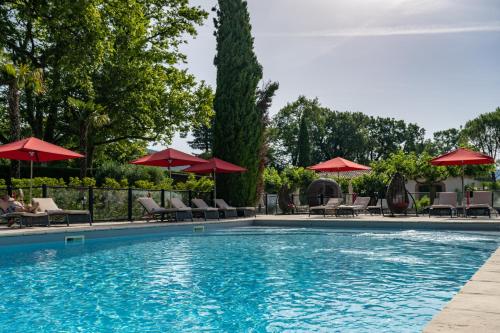 a swimming pool with chairs and umbrellas at Le Domaine Du Colombier in Malataverne