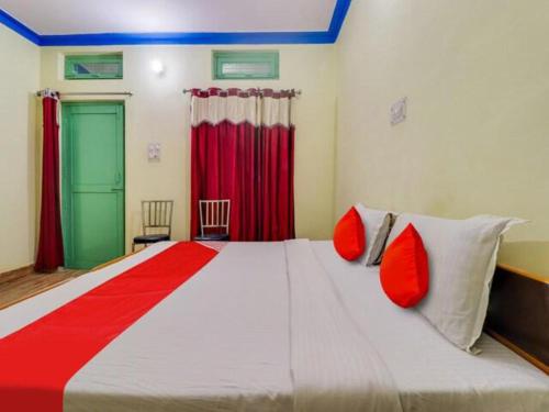 a bedroom with a large bed with red pillows at Hotel Abhinandan in Phata