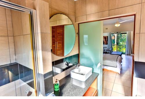 a bathroom with a sink and a shower and a bed at RR001 Robbins Road - A home away from home in Ballito