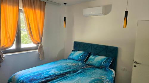 a bedroom with a bed with blue sheets and a window at Apartments Villa Joja in Međugorje