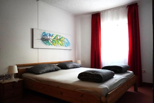 a bedroom with a bed and a window with red curtains at Apartments Krnjic in Umag