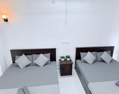 two beds with pillows and a table in a room at NO 10 Kandy by Kepler & Earth in Kandy