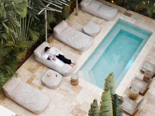 a woman laying on a couch next to a swimming pool at Hotel Anilevich Mansion in Beer Sheva