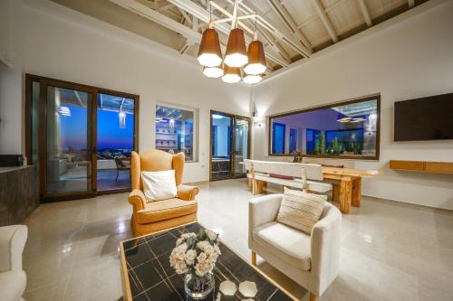 a living room with chairs and a table and a pool table at Villa Kedria with a panoramic ocean view in Souda