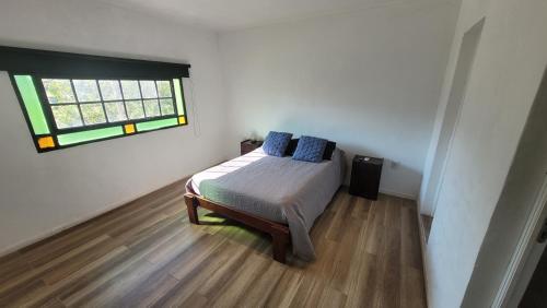 a bedroom with a bed with blue pillows and a window at El Puente Tierra de Sueños 3 in Roldán