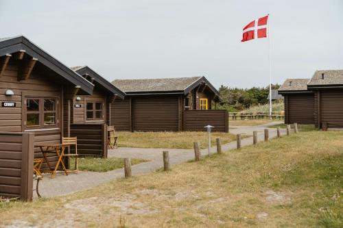 a row of wooden cabins with a flag on top at A Small Wooden Hut In A Large Community in Ulfborg
