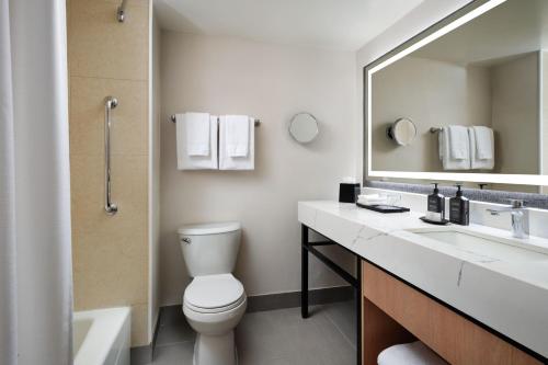 a bathroom with a toilet and a sink and a mirror at Sheraton Ontario Airport Hotel in Ontario