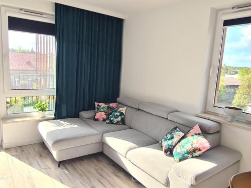 a living room with a couch and two windows at Modrzewiowy Zakątek in Augustów