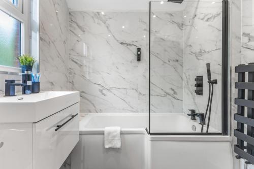 a white bathroom with a shower and a sink at Modern City Centre Townhouse sleeps 10 & Parking in Manchester
