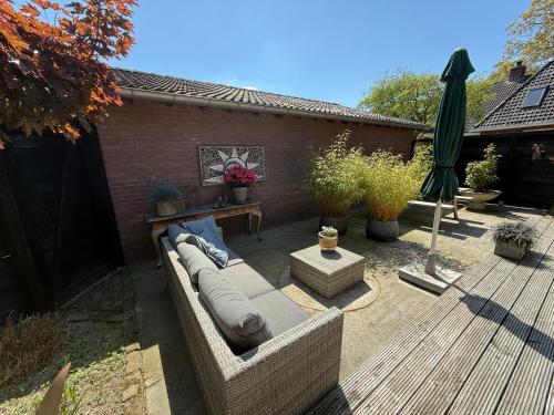 a patio with a couch and a table and umbrella at Bed en Breakfast Het Oelenest in Hooghalen