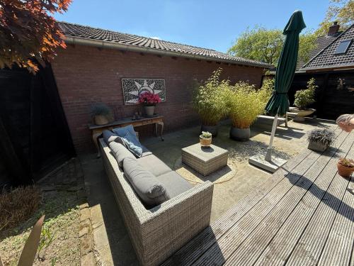 a patio with a couch and a wooden deck at Bed en Breakfast Het Oelenest in Hooghalen