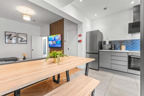 a kitchen with a wooden table and a refrigerator at Modern City Centre Townhouse sleeps 10 & Parking in Manchester