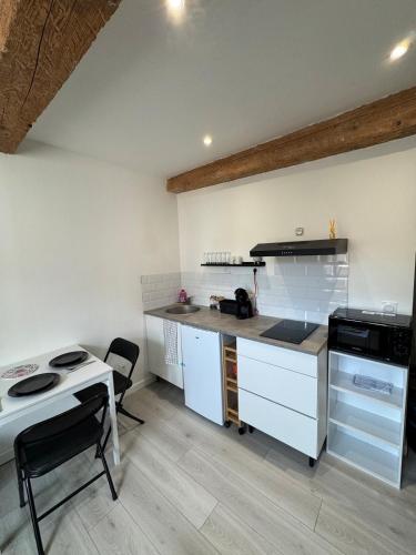 une cuisine avec des armoires blanches et un comptoir dans l'établissement La perle centrale - Studio, à Limoux