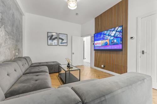 a living room with a couch and a flat screen tv at Modern City Centre Townhouse sleeps 10 & Parking in Manchester