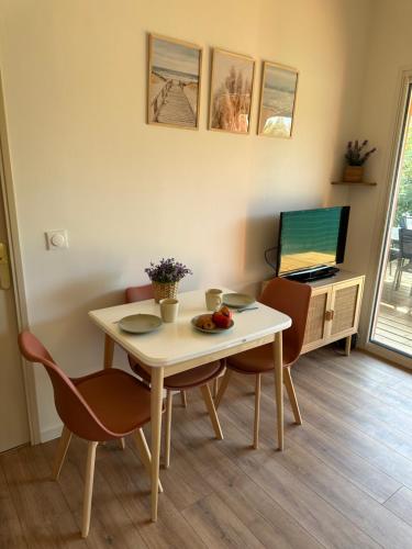 un salon avec une table, des chaises et une télévision dans l'établissement Maison de vacances en Camargue, à Aigues-Mortes