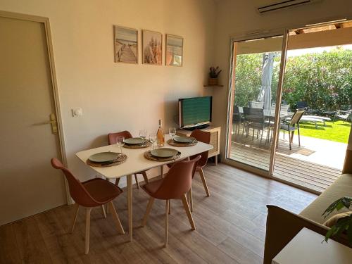 une salle à manger avec une table, des chaises et une télévision dans l'établissement Maison de vacances en Camargue, à Aigues-Mortes