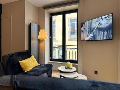 a living room with a couch and a flat screen tv at Cocon en centre ville in Le Puy en Velay