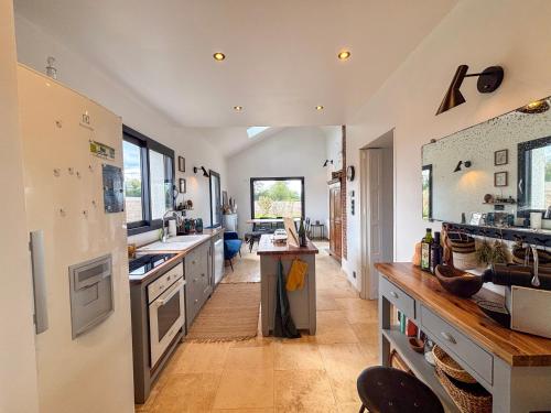 une grande cuisine avec des comptoirs blancs et un grand réfrigérateur dans l'établissement Cottage romantique dans les champs, à Bonsmoulins