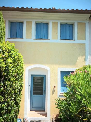 une maison avec une porte bleue et deux fenêtres dans l'établissement La Cigale, à Grimaud