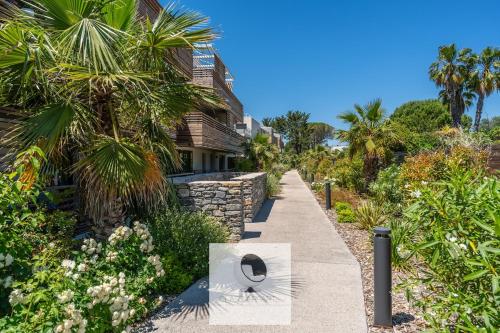 a walkway in front of a house with palm trees at Appartement avec grande terrasse et spa à Lattes in Lattes