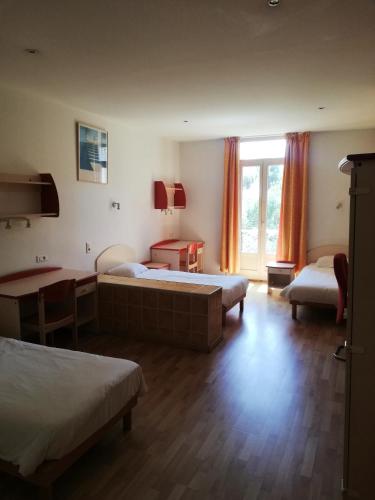 une chambre avec deux lits et une table et une fenêtre dans l'établissement Campus Santa Maria, à Cannes