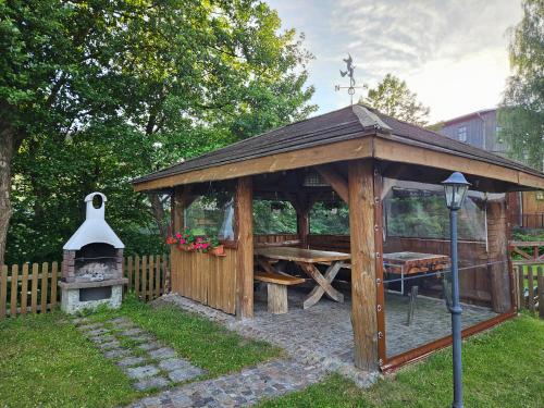 a wooden gazebo with a table and a grill at Chata Pod Strzechą in Lipusz