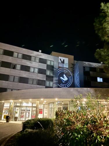 a building with a clock on the side of it at Le M & Spa Bordeaux Aéroport by Hôtels & Préférence in Mérignac