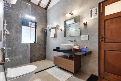 a bathroom with a sink and a toilet and a mirror at Luxury farm villa with pool near Mumbai in Zadapoli