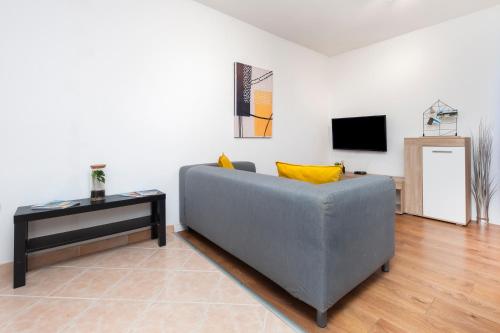 a living room with a gray couch and a tv at Apartments Luce in Rovinj