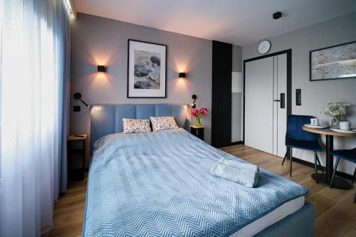 sypialnia z łóżkiem z niebieską kołdrą w obiekcie Apartamenty i Pokoje Złotobrzeg w Sarbinowie