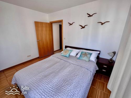 a bedroom with a bed with birds on the wall at Baltic Zen II - Apartament in Hel