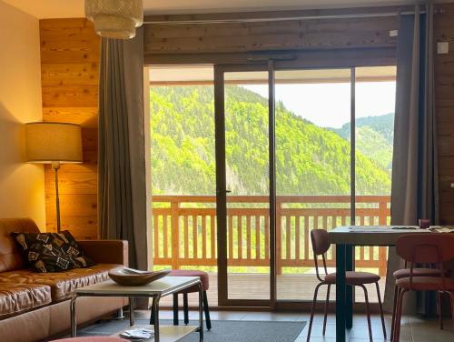 un salon avec un canapé et une grande fenêtre dans l'établissement Appartement charmant au pied des pistes, à Saint-Jean-dʼAulps