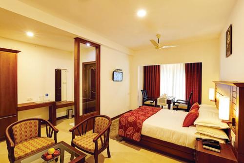 a hotel room with a bed and a table and chairs at Spice Residency Thekkady in Vandanmedu